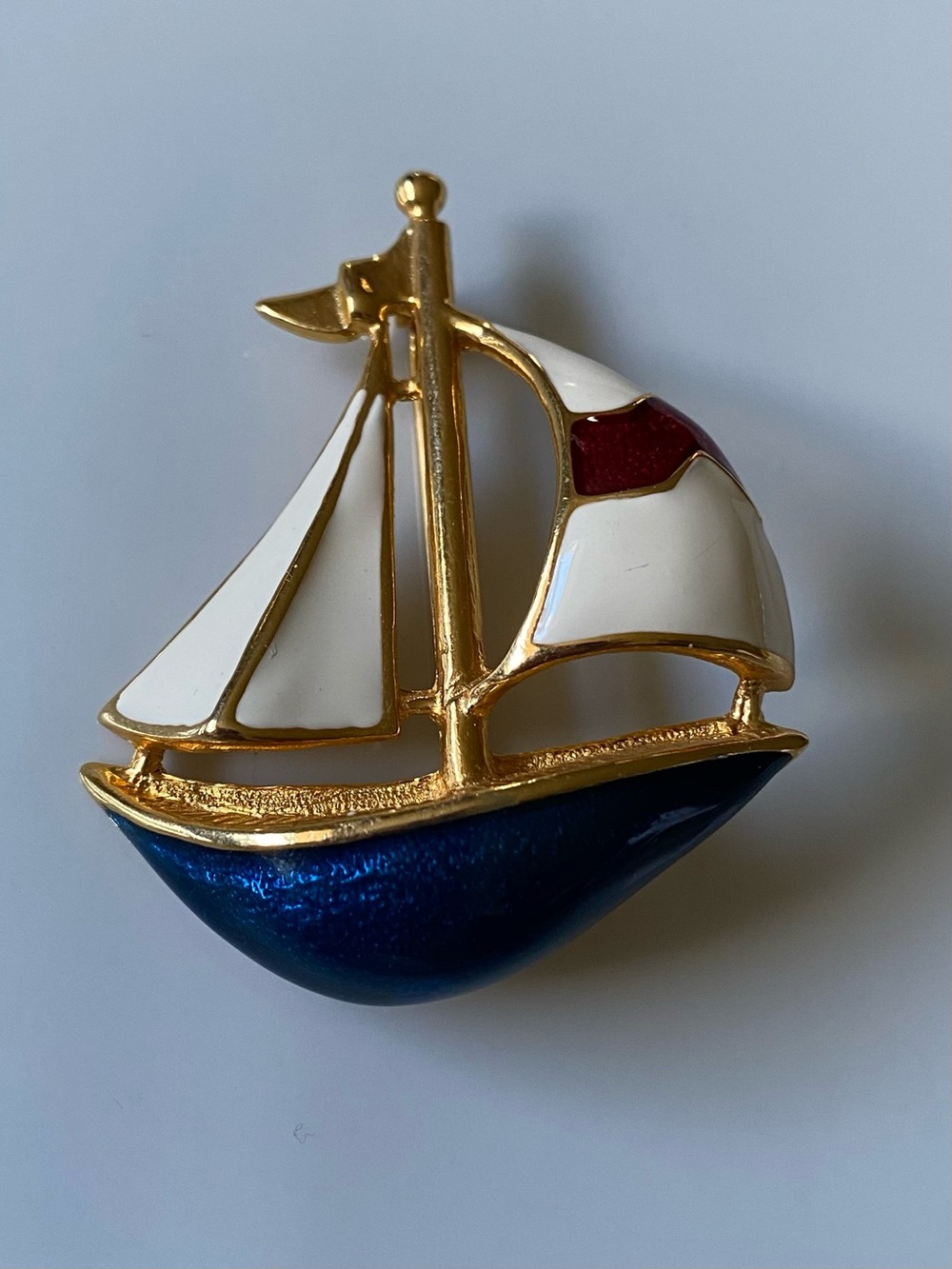 A gold-tone and enamel sailboat brooch.